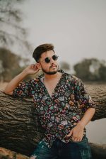 Home Fashionable man in casual wear leaning on a tree outdoors in Delhi, India.