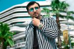 Home Close-up portrait of a fashionable man in sunglasses and striped shirt outdoors under a clear sky.